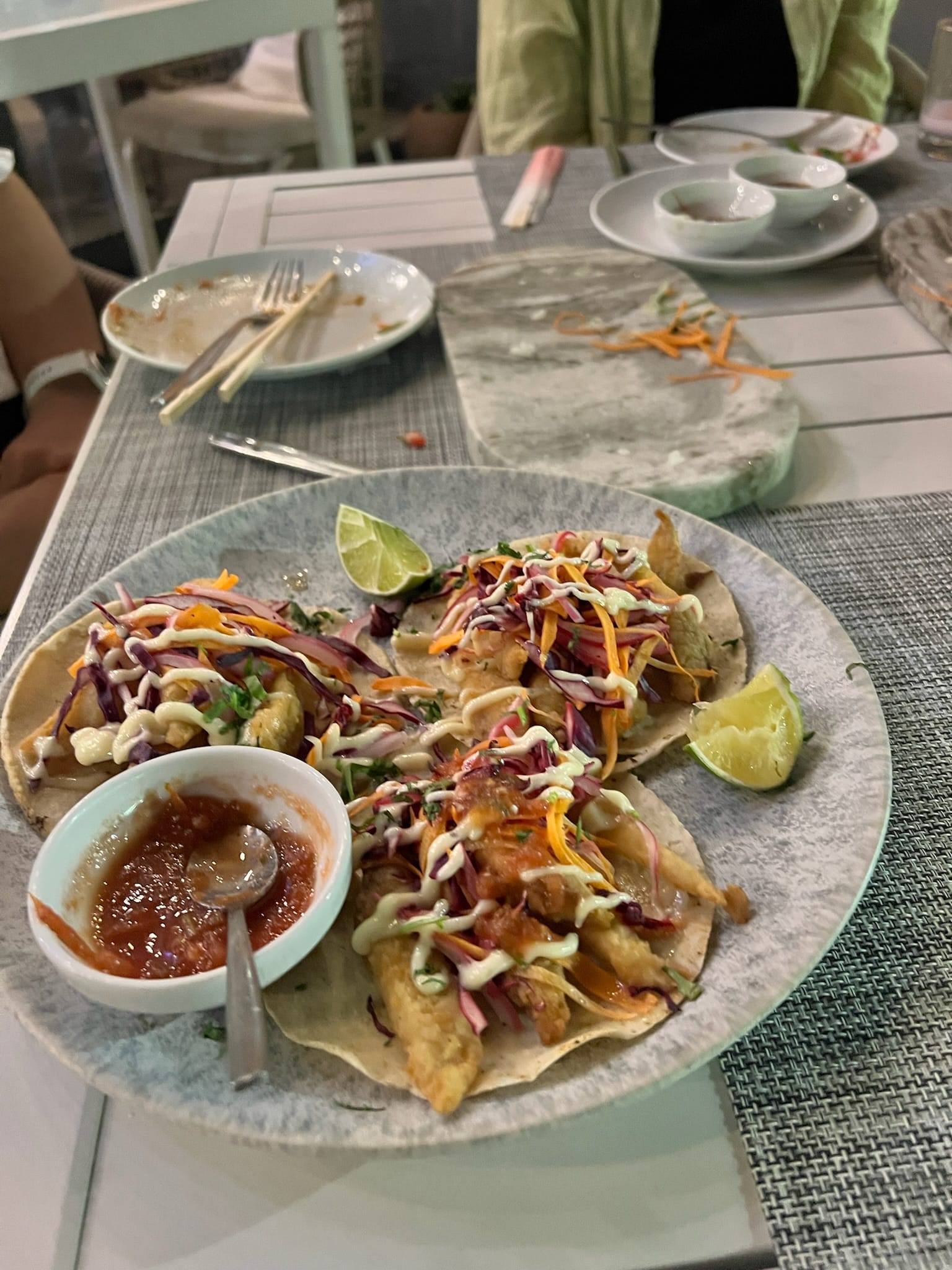 A plate of fish tacos with lime and salsa