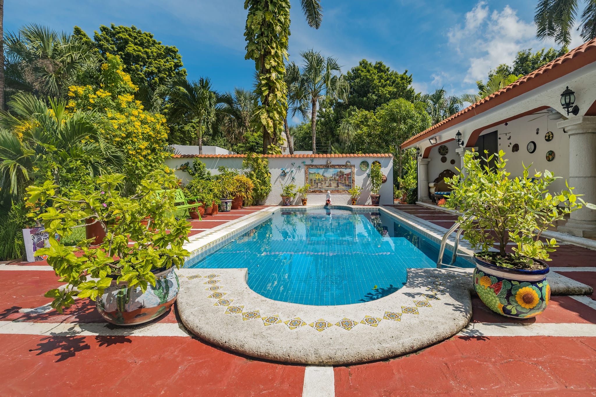 A tiled pool ringed with Talavera pots and a red patio