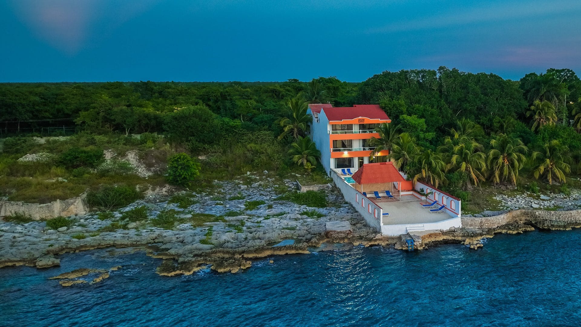 A home on the coral shore north of town at dusk, seen from the water