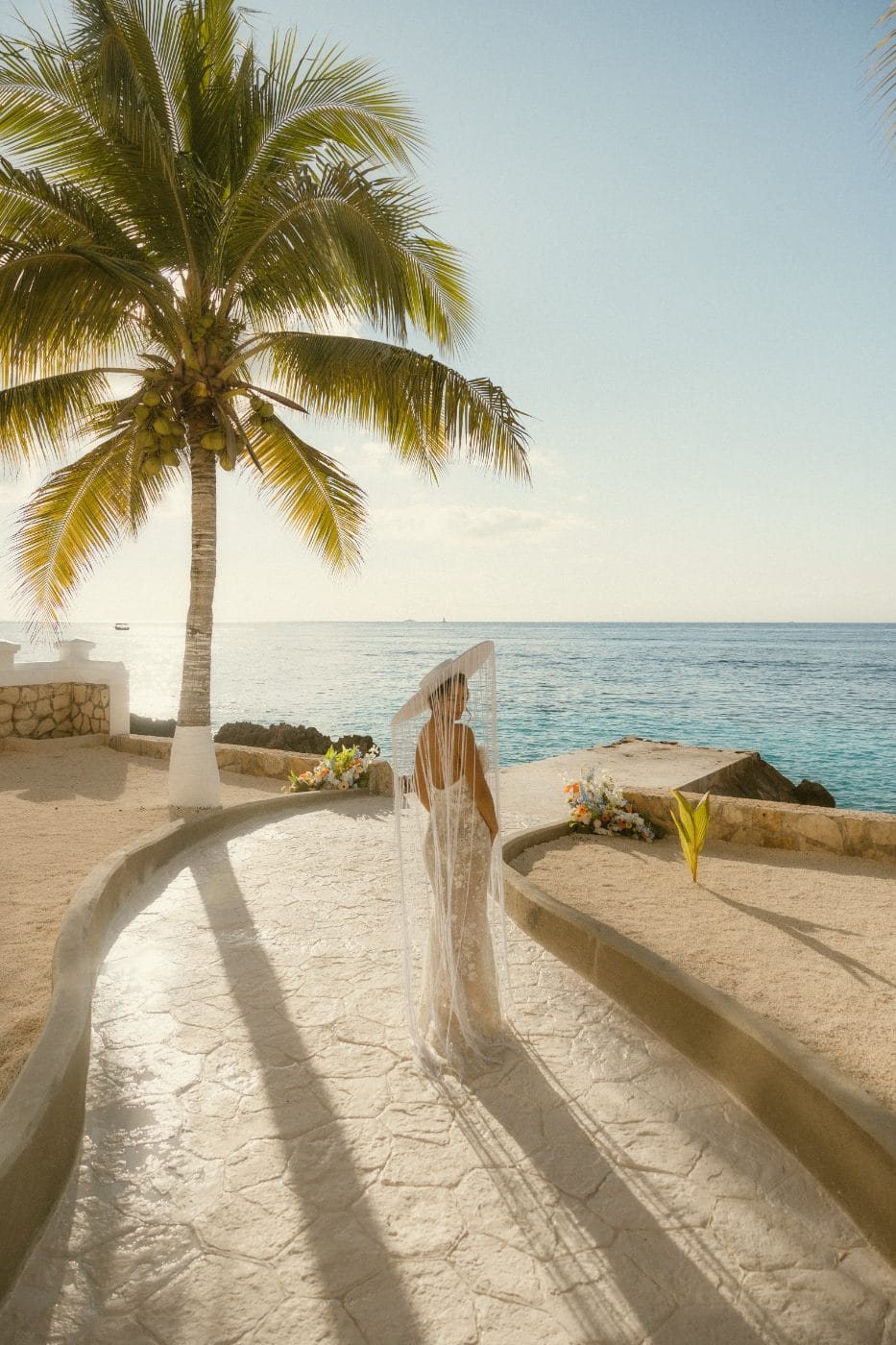 A couple on the pier after the ceremony, flowers along the sand wall