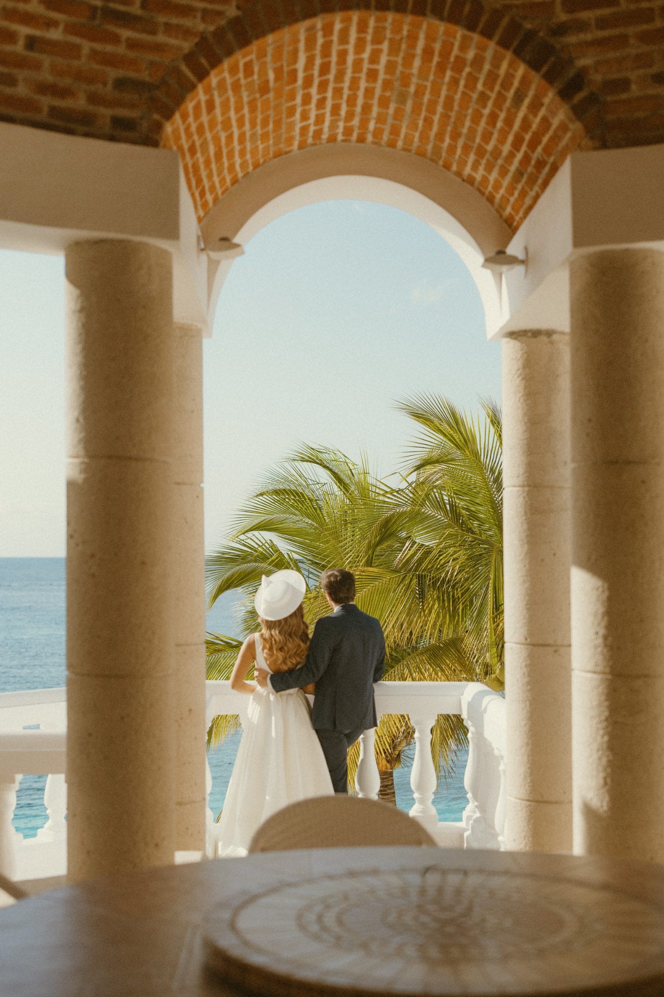 A couple dancing on the pier, flowers along the wall and open water beyond